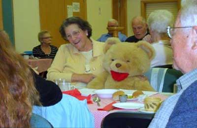 resident and teddie bear at harvest meal